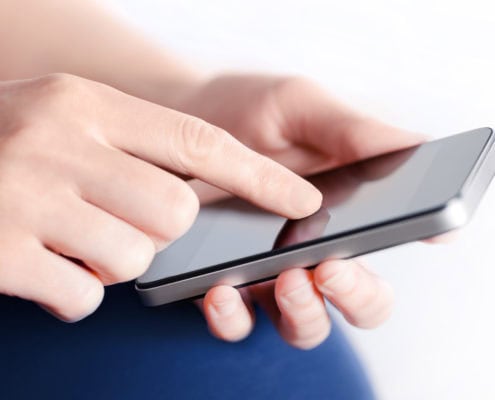 Girl hand touching screen on modern mobile smart phone. Close-up image with shallow depth of field focus on finger.