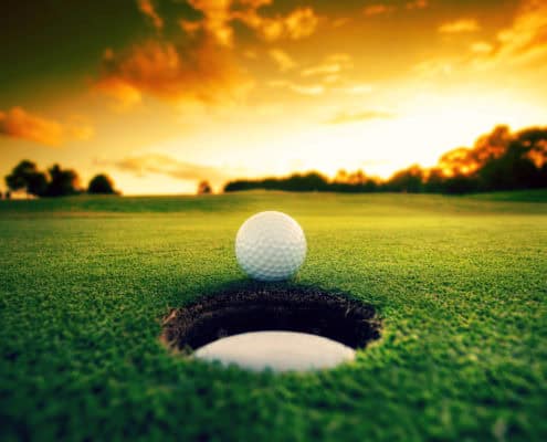 Golf ball about to fall into the cup at sunset